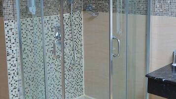 Een aparte badkuip en douche, een diep bad, een regendouche