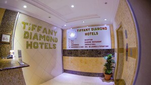 A reception area with a sign for Tiffany Diamond Hotels, listing amenities like a reception, conference rooms, and a restaurant.