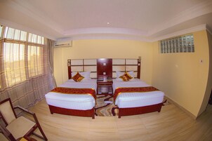 Habitación de hotel con dos camas, cabecero de madera, una mesita y una silla.
