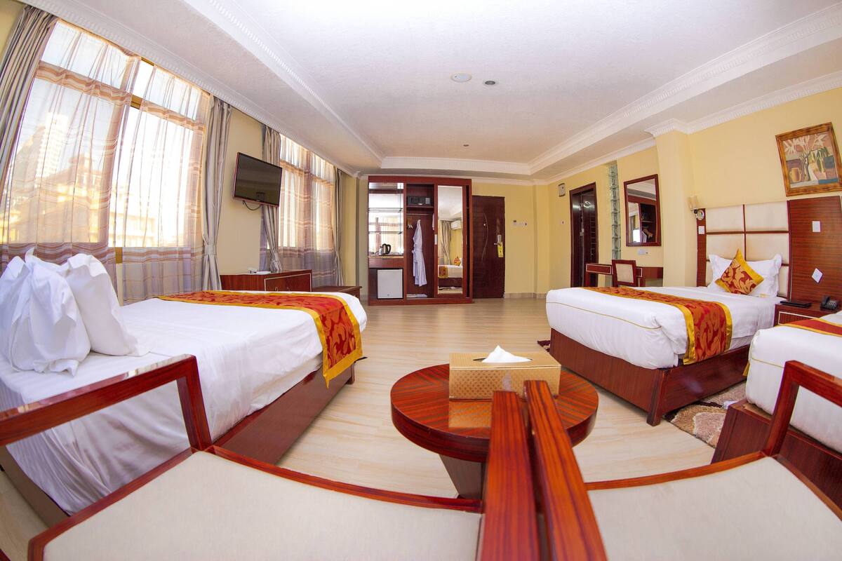 A hotel room with two beds, a TV, a desk, and a mirror.
