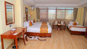 A hotel room with a large bed, a desk, two chairs, and a small sofa.