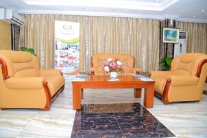 A lobby with two leather armchairs, a wooden coffee table, and a banner.