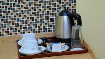 A tray with a coffee maker, cups, and sugar packets on a tiled countertop.