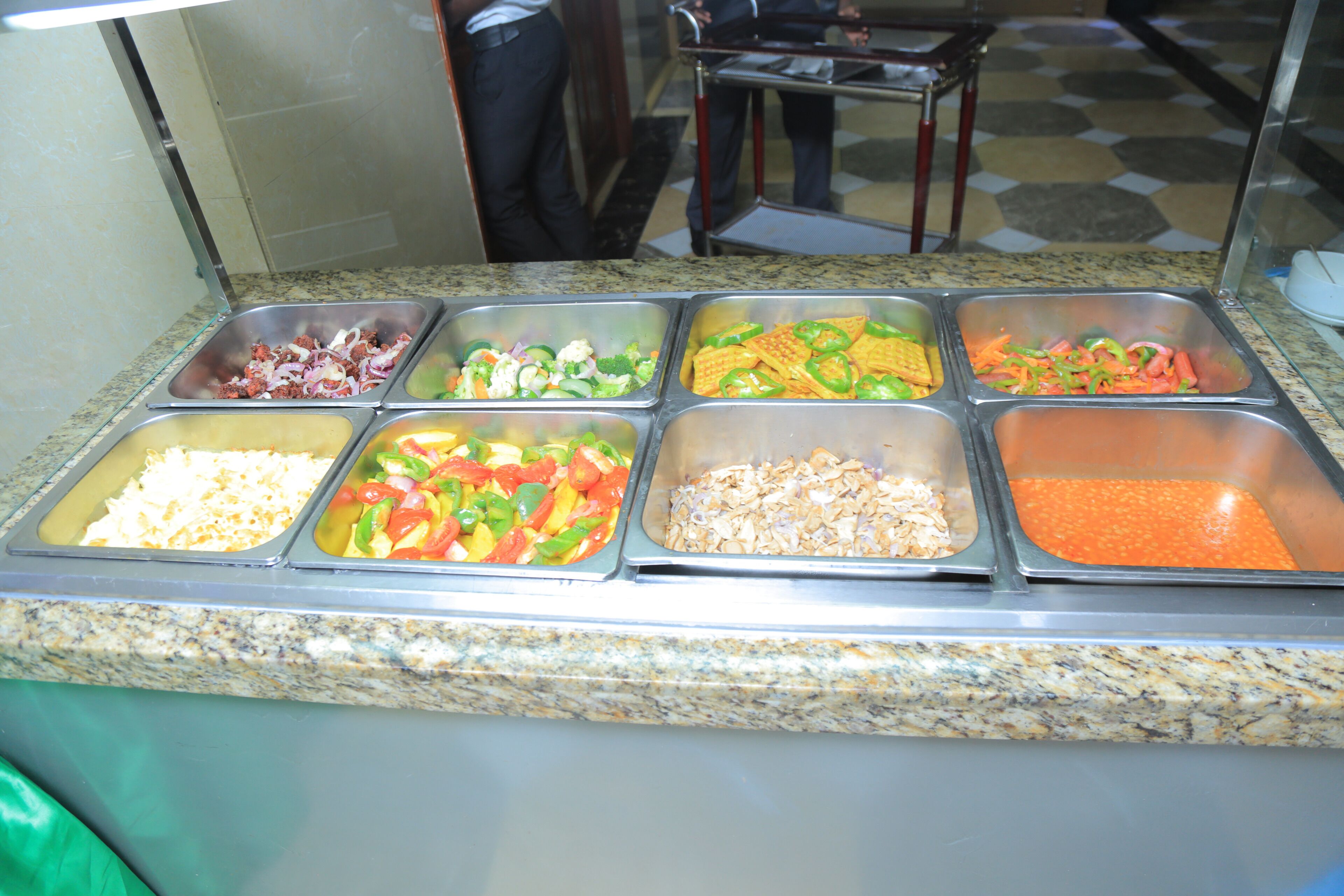 A buffet with various food items including salads, vegetables, and grains.