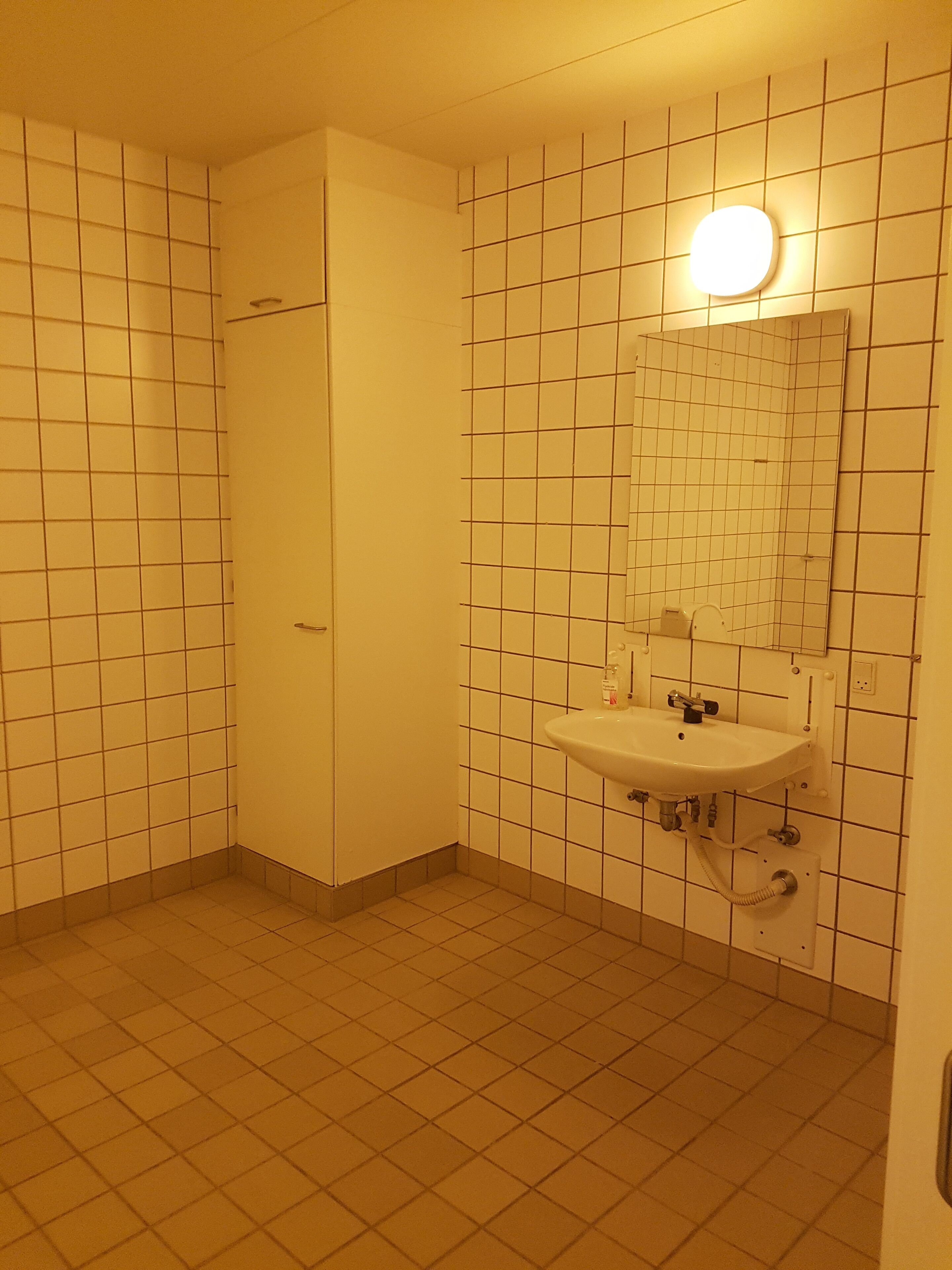 A bathroom with a tiled floor, a sink with a mirror, and a door.