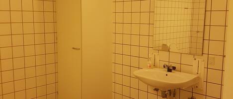 A bathroom with a tiled floor, a sink with a mirror, and a door.