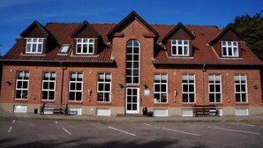 A two-story brick building with a symmetrical facade, large windows, and a central entrance. - Danhostel Brande (Brande)
