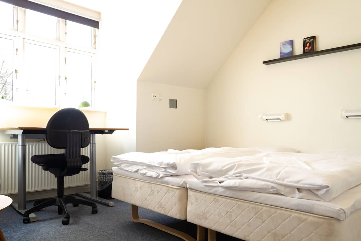 A room with a bed, a desk, and a chair.