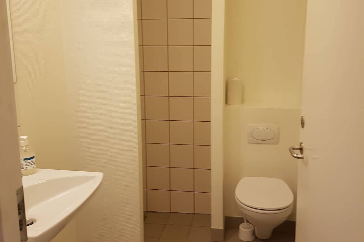 A narrow bathroom with a white sink, toilet, and tiled walls.