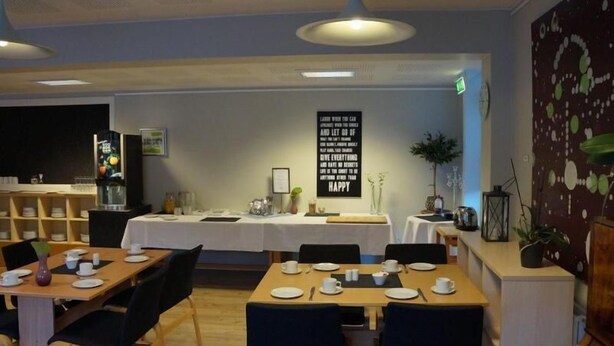 A restaurant with tables set for dining, a large motivational quote on the wall, and a decorative plant on the right. - Danhostel Brande (Brande)