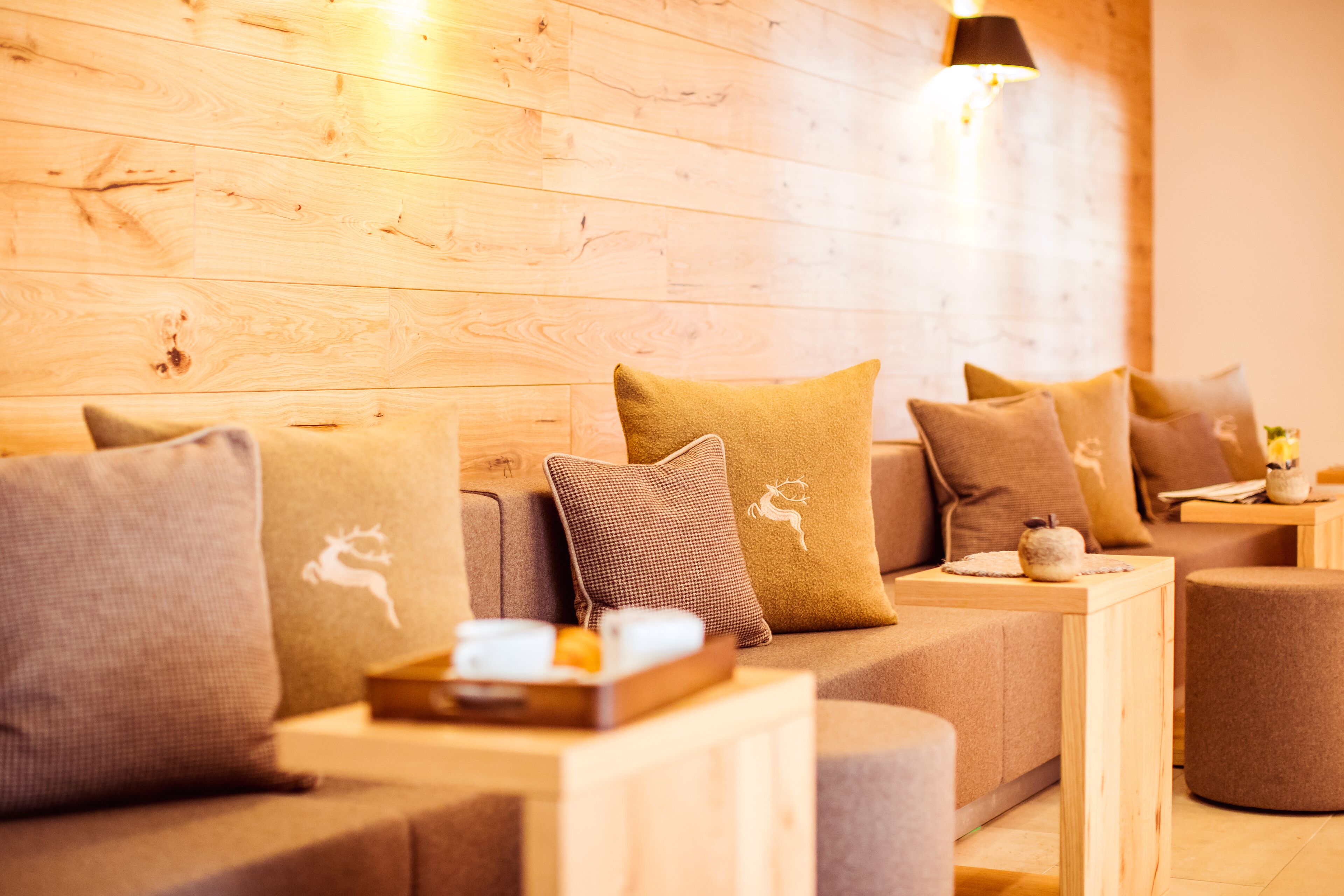A cozy seating area with a wooden wall, a sofa with multiple cushions, and a small table with a tray.