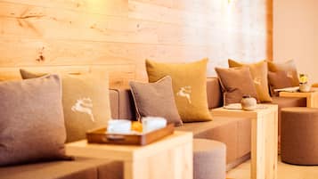 A cozy seating area with a wooden wall, a sofa with multiple cushions, and a small table with a tray.