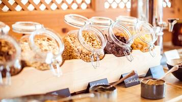 Ein Buffet mit verschiedenen Speisen in Glasbehältern, darunter Granola und Schokoladenstückchen.