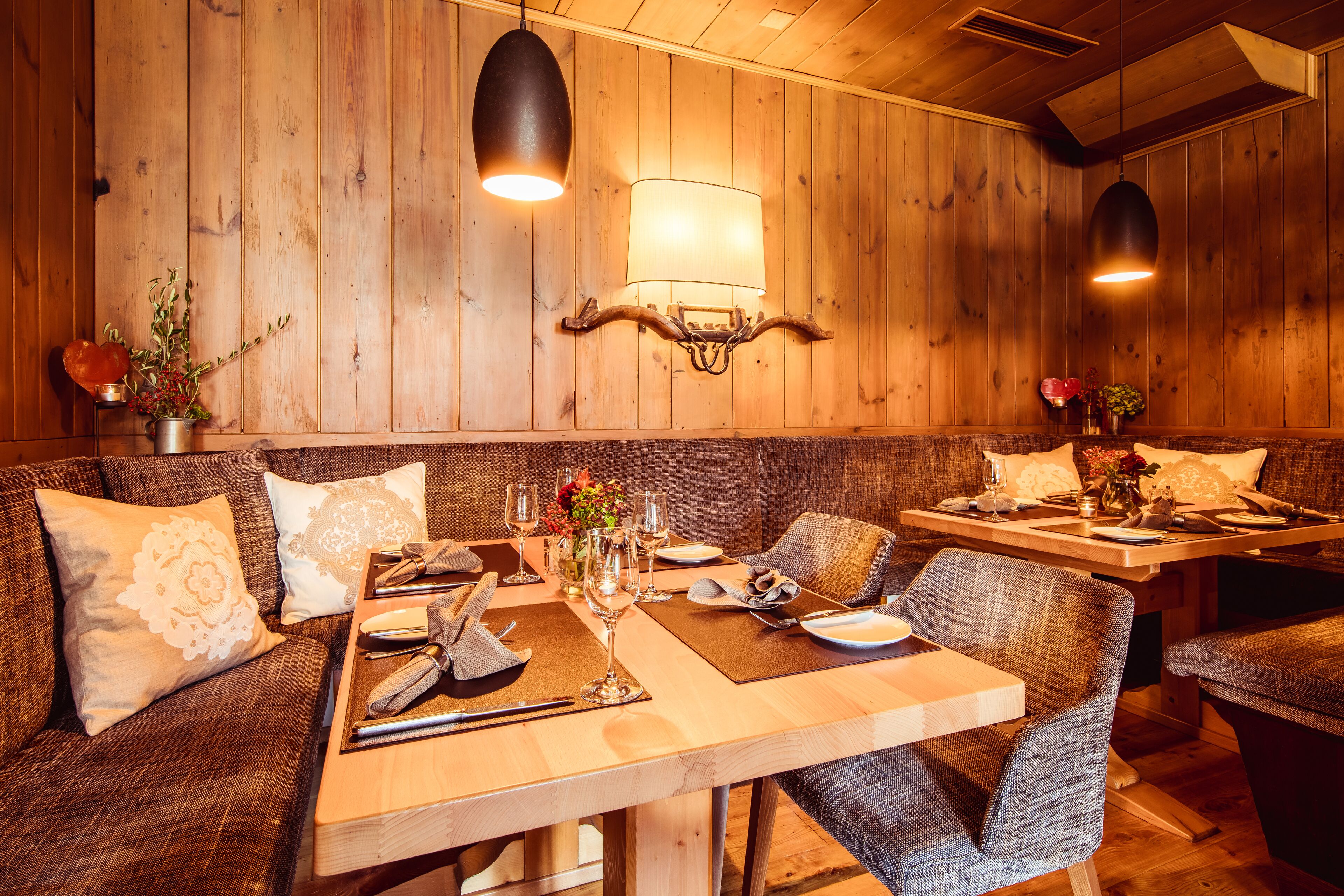 A wooden interior with a dining table set for two, surrounded by upholstered seating.