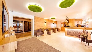 Een moderne hotellobby met houten lambrisering, een receptiebalie, een zithoek en een receptiecounter.