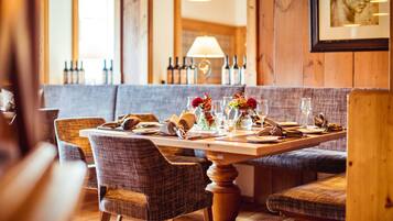 A restaurant interior with a wooden table set for dining, upholstered chairs, and a bench.