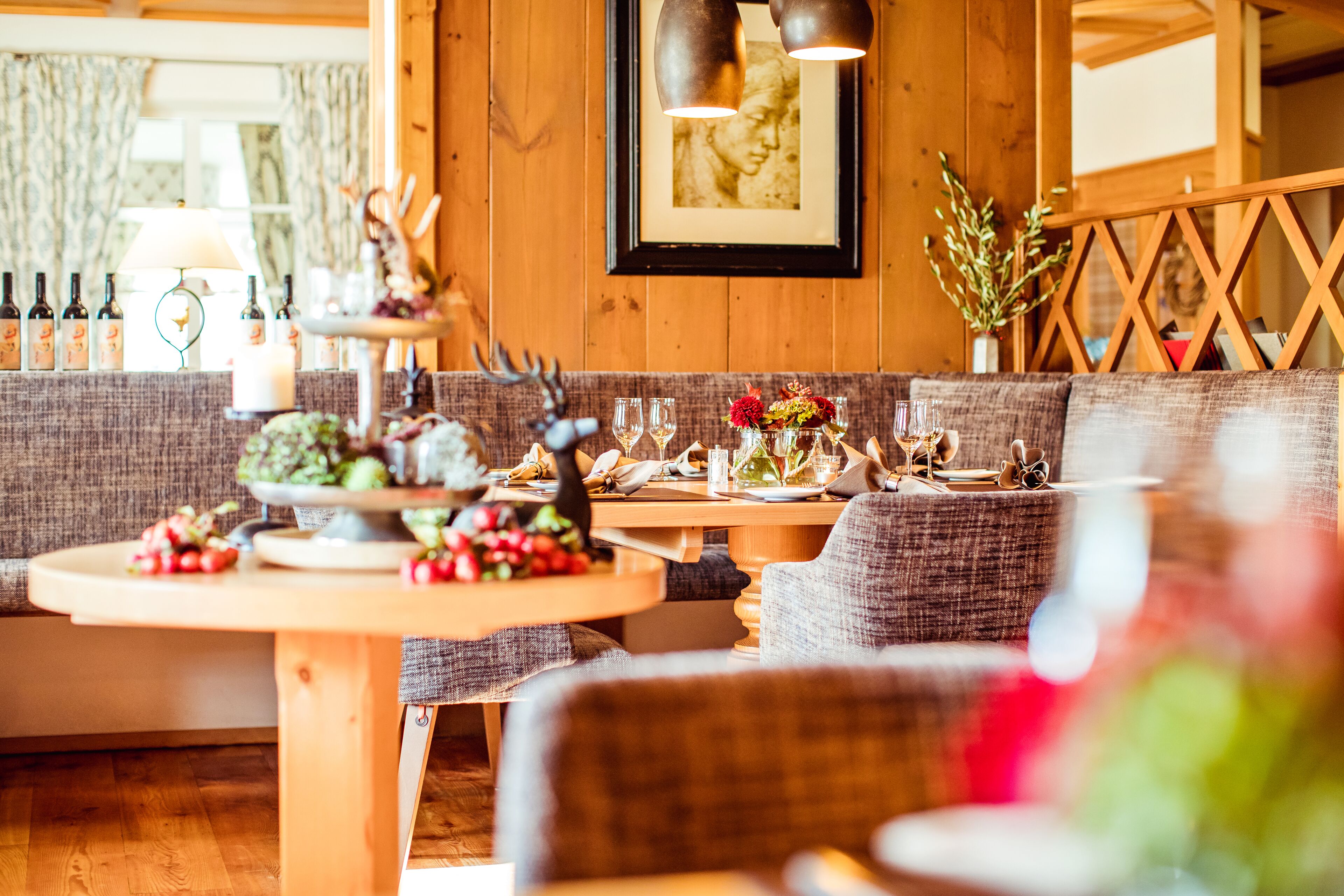 Un comedor acogedor con muebles de madera, una mesa dispuesta con copas de vino, una vela y un cuadro en la pared.