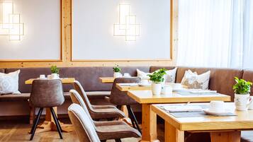 A cozy cafe with wooden furniture, tables with white cups, and a wooden floor.