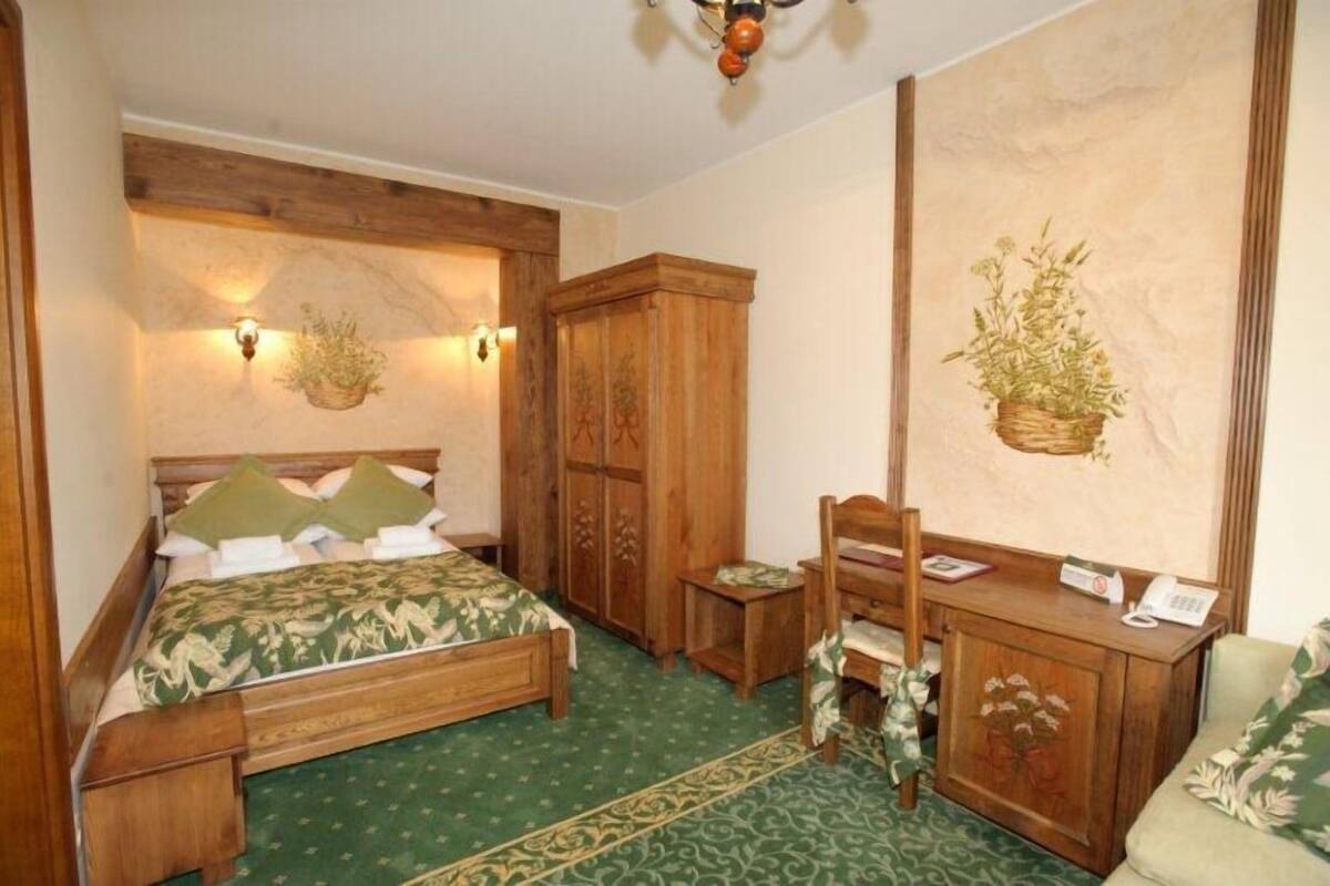 Une chambre traditionnelle avec un lit en bois, un bureau et une chaise. On y trouve également un meuble contenant un téléphone et une lampe fixée au mur.