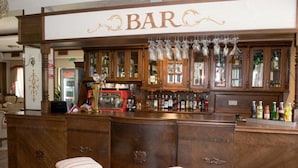 A bar area with wooden cabinets, a Coca-Cola refrigerator, and a selection of bottles.
