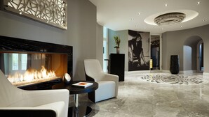 Eine moderne Lobby mit Kamin, Sitzgelegenheiten, einer Dekoration an der Wand und einem gemusterten Boden.