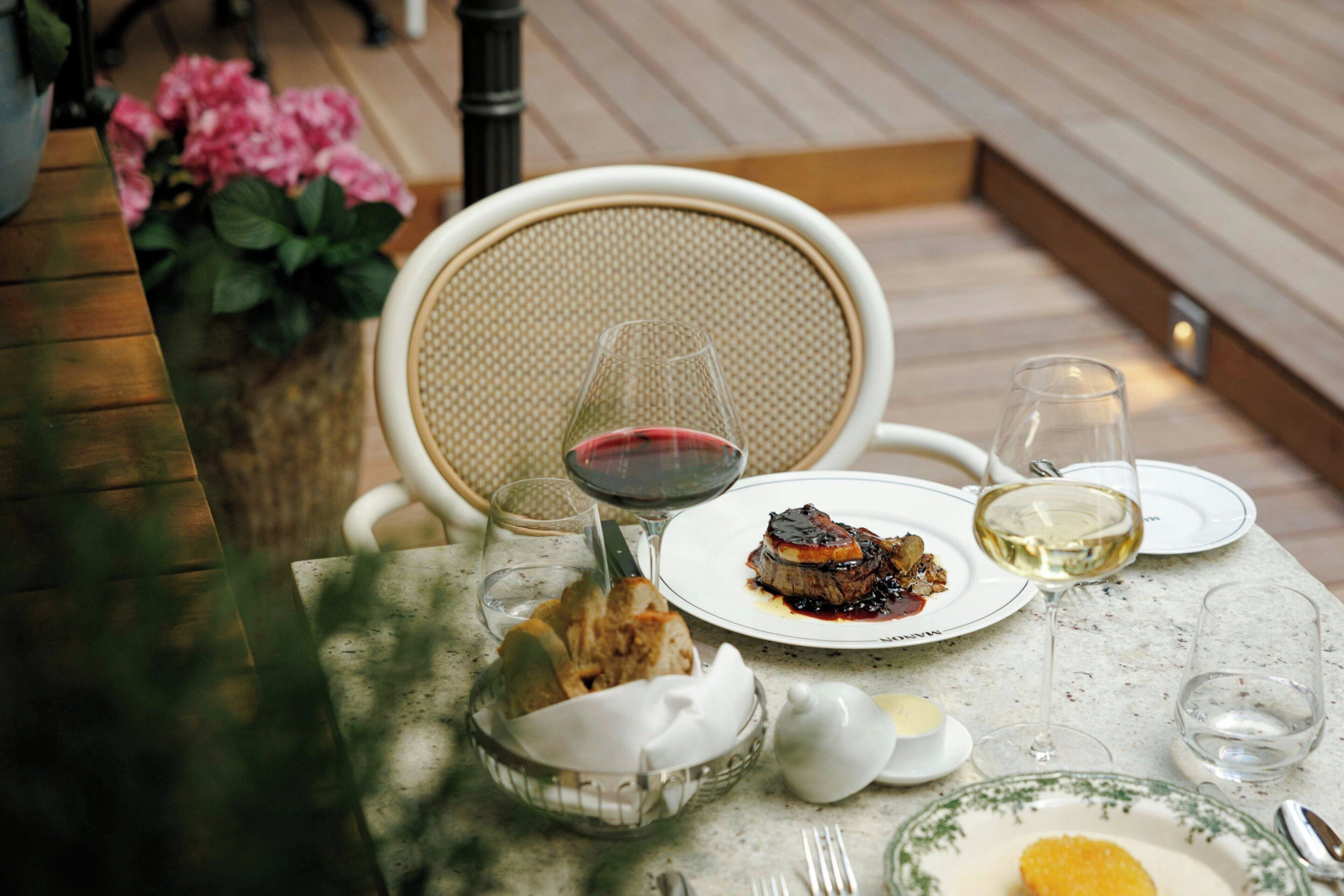 A dining table with a plate of food, a glass of red wine, and a glass of white wine.