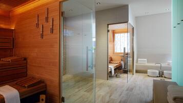 A modern spa room with wooden benches, a glass partition, a sauna, and a bathroom with a bathtub and sink.