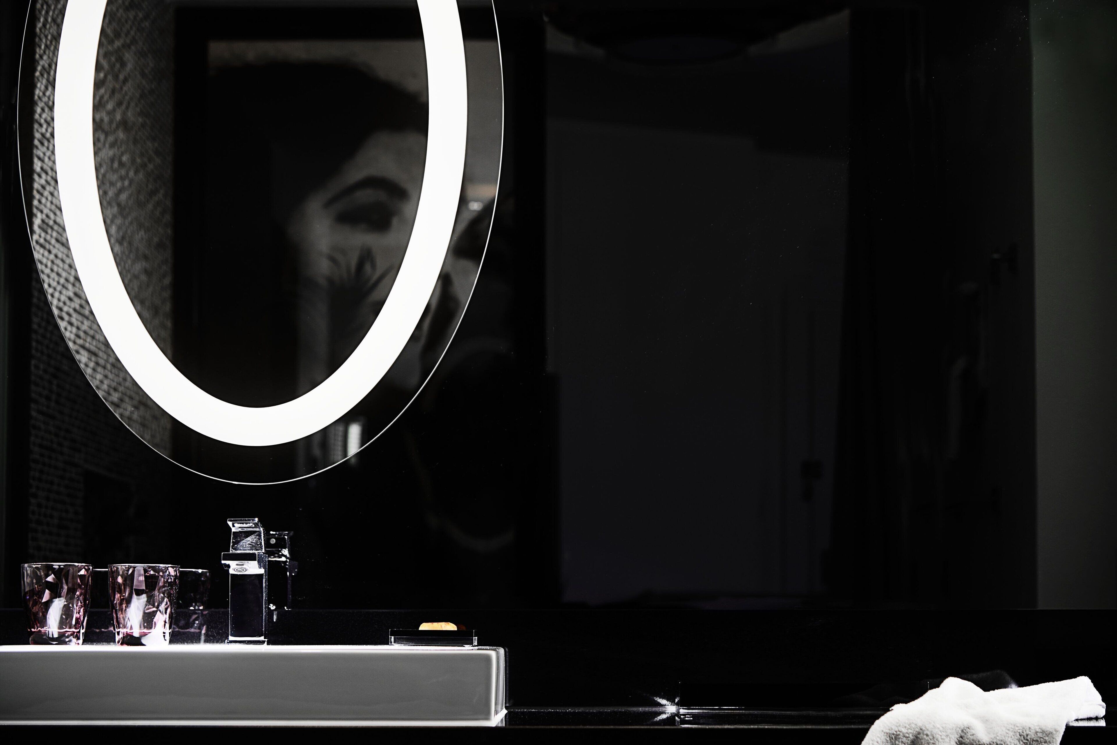 A bathroom with a large mirror, a sink, and three glasses.