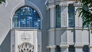 Ein Gebäude mit einer geschwungenen Fassade, großen Bogenfenstern und dekorativen Gesimsen.