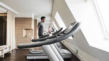 Une salle de sport moderne, équipée de tapis de course et d’un vélo d’appartement, dotée de grandes fenêtres et d’un intérieur en bois.