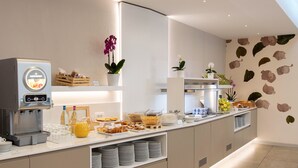 A modern breakfast bar with a coffee machine, fruit, pastries, and decorative plants. - Affittacamere Piazza (Verbania)