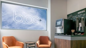 A modern bbc coffee shop with two cushioned chairs, a small round table, and a Nescafé coffee machine. - Bloc Hotel London Gatwick Airport (Gatwick)