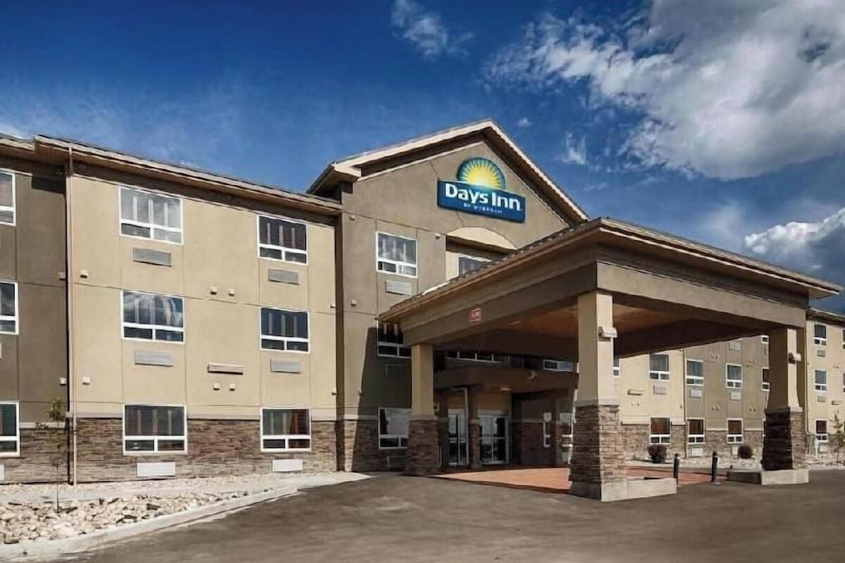 Een Days Inn hotel met een overdekte ingang, meerdere ramen en een gevel van natuursteen.
