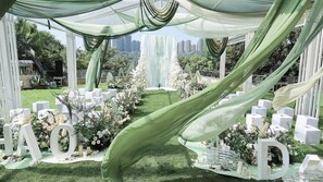 Montaje de boda al aire libre con arreglos florales blancos, una zona con césped y letras blancas de gran tamaño que deletrean 'LOVE'.