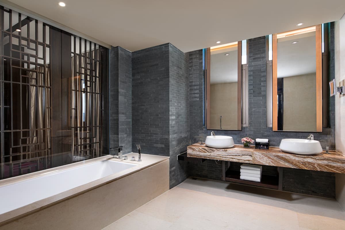 A modern bathroom with a large bathtub, two sinks, and a large mirror.