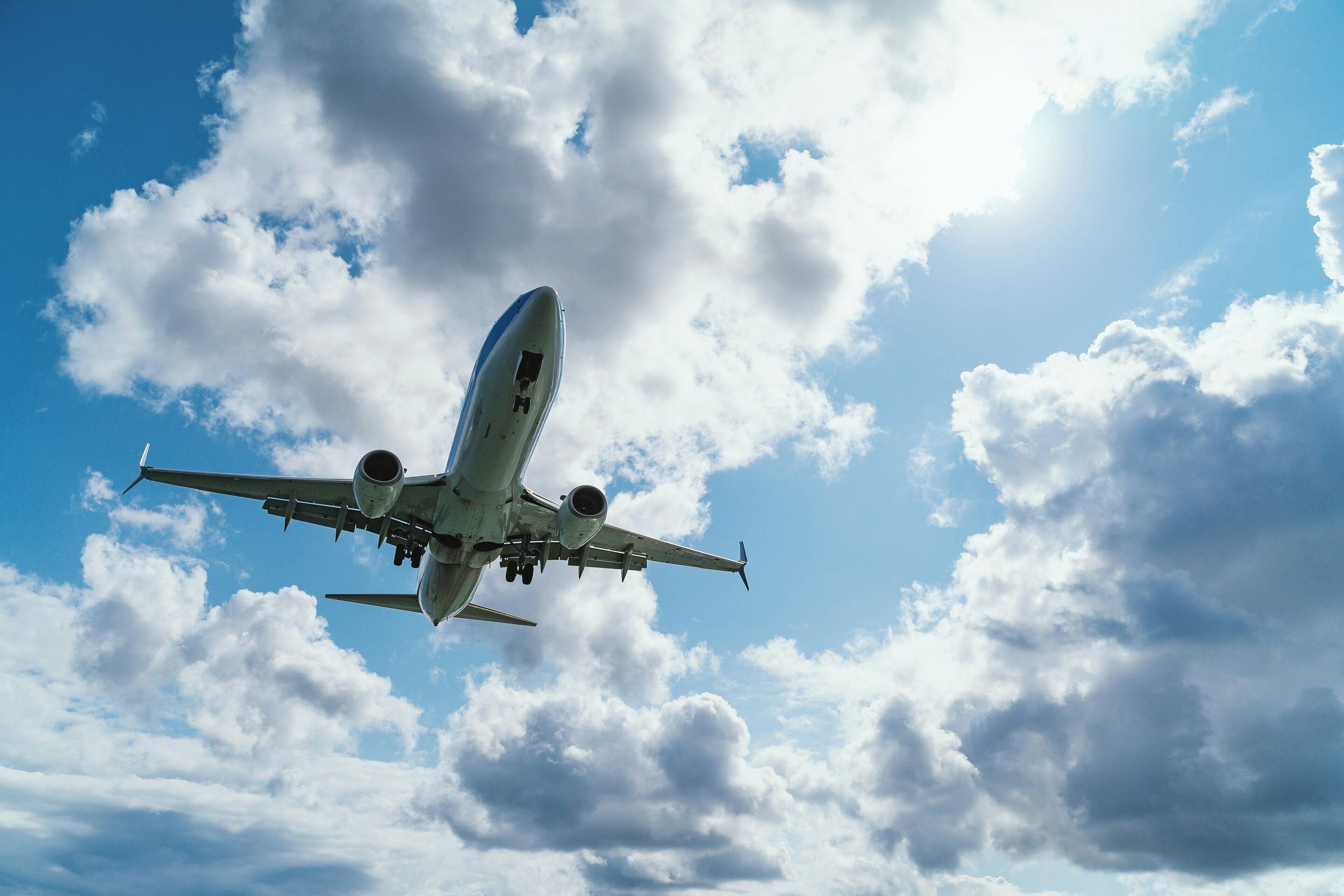 Un avión volando por un cielo con nubes dispersas.