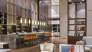 A modern hotel lobby with a bar area, seating, and a bookshelf. - Crowne Plaza Chongqing New North Zone by IHG (Chongqing)