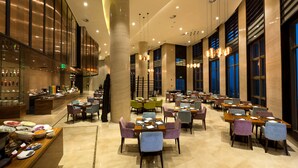 A spacious hotel lobby with multiple dining areas, a bar, and a buffet with various food items. - Crowne Plaza Chongqing New North Zone by IHG (Chongqing)