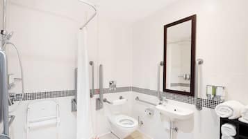 A modern bathroom with a shower, toilet, sink, and a large mirror.