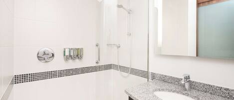 Une salle de bain moderne avec une douche carrelée de carreaux blancs, un lavabo sur un plan de travail en granit et un miroir avec un cadre en bois.