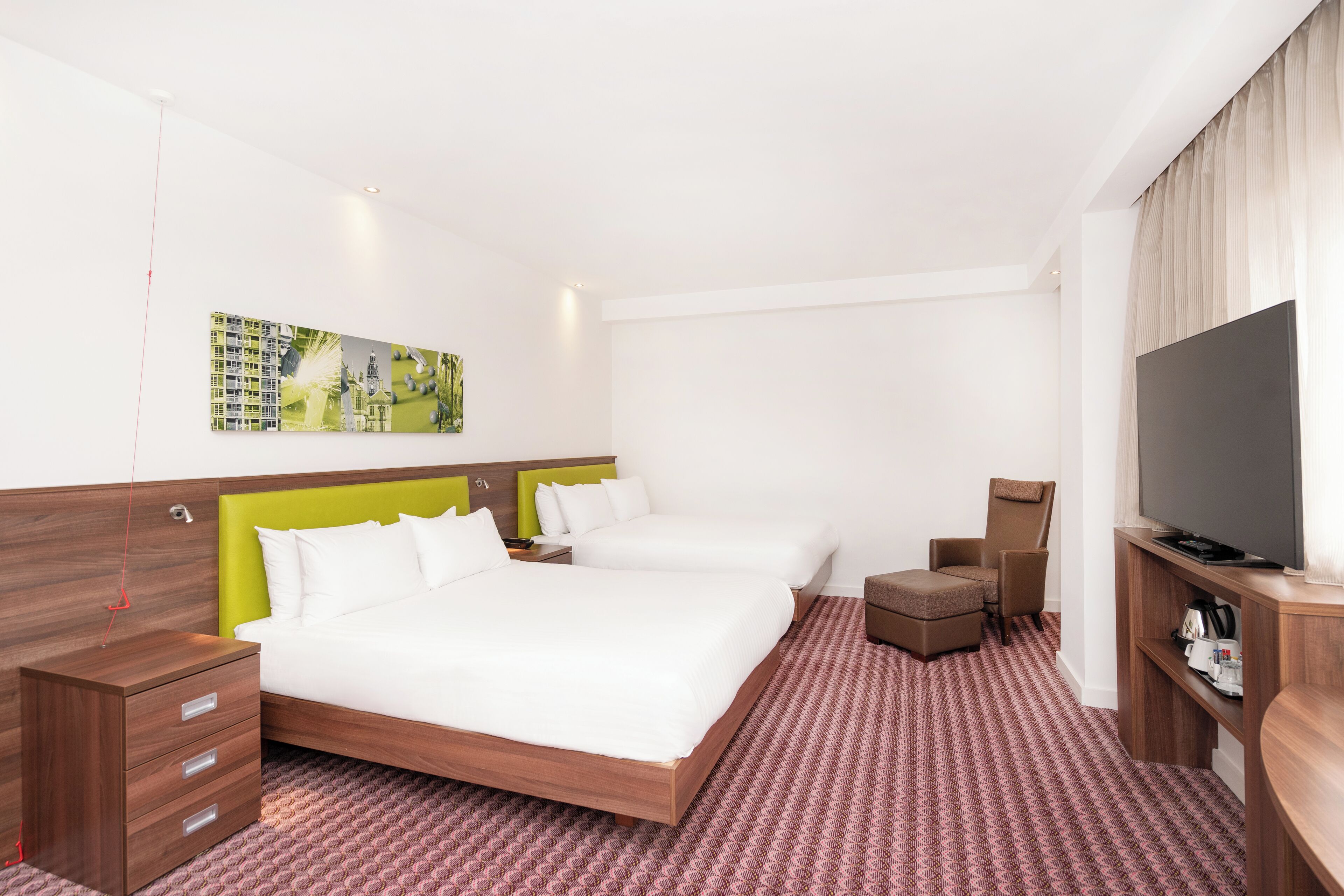 A hotel room with two beds, a TV, a desk, and a chair.