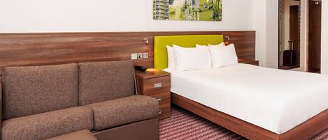 Ein Hotelzimmer mit einem Bett, einer Couch, einem kleinen Tisch und einem Wandbild.