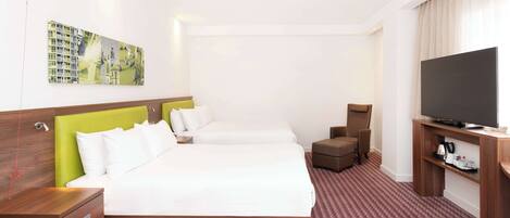 Ein Hotelzimmer mit einem großen Bett, einem Fernseher, einem Schreibtisch und einem Sessel.