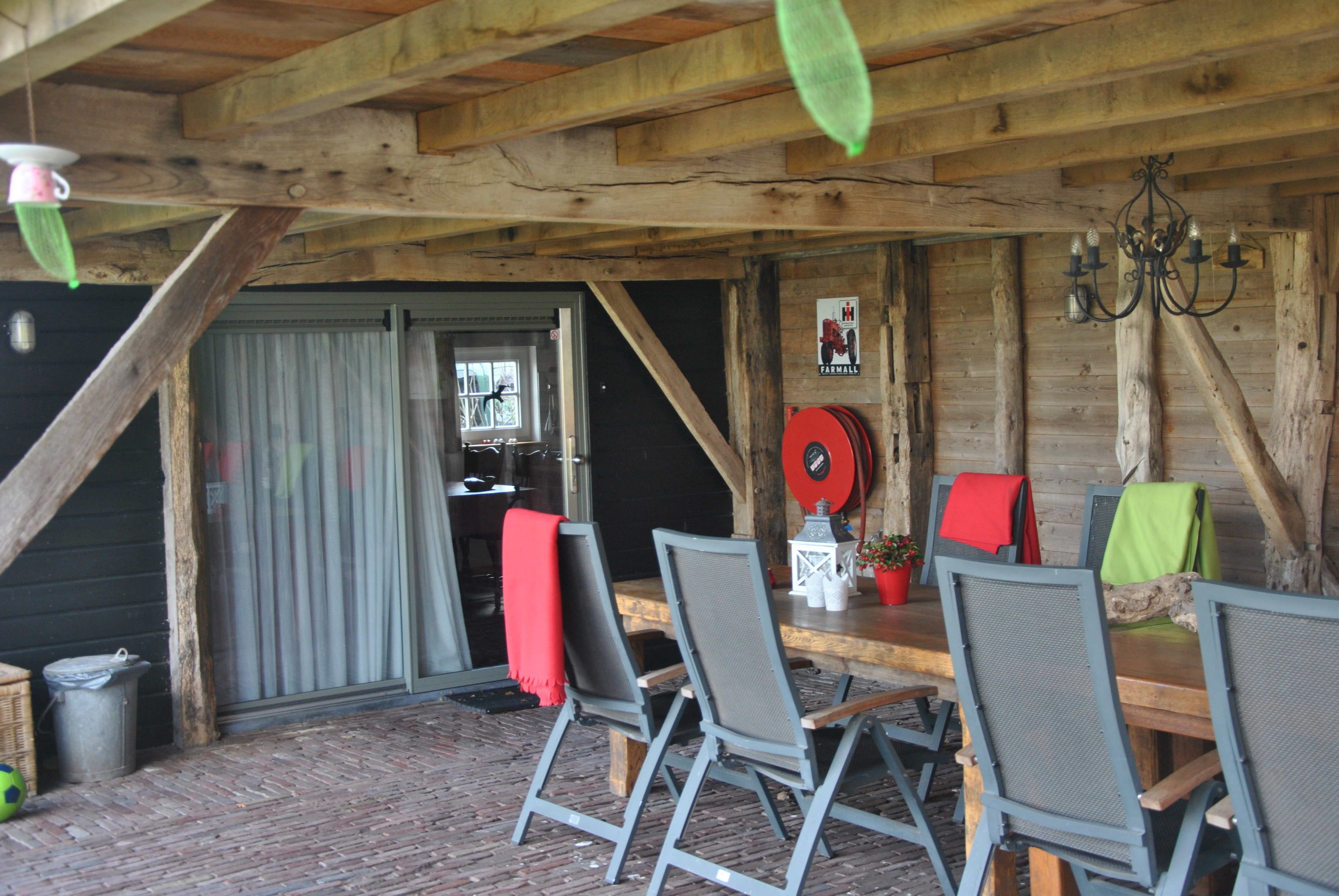 Un coin repas rustique en bois, avec une table et des chaises, un lustre et une porte donnant sur l’extérieur.