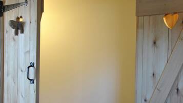 A wooden room with a bed, a small window, and a wooden door.