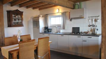 A kitchen with wooden chairs, a dining table, white cabinets, and a window with curtains.