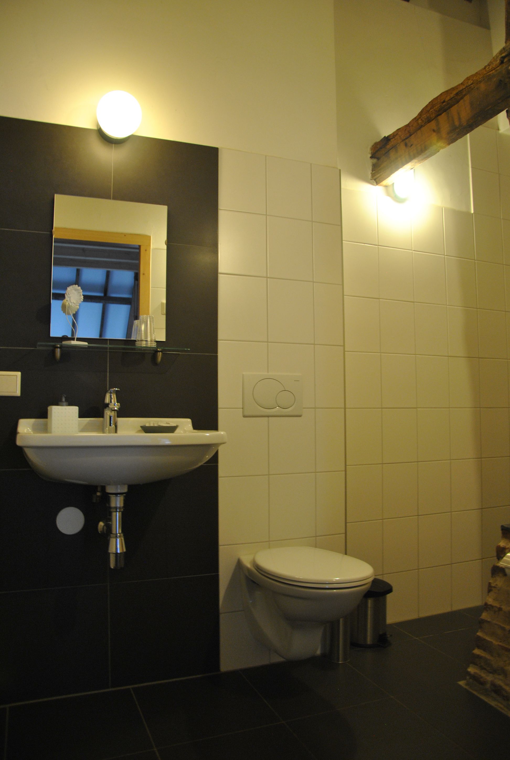 A bathroom with a white sink, a mirror, a toilet, and a trash can.