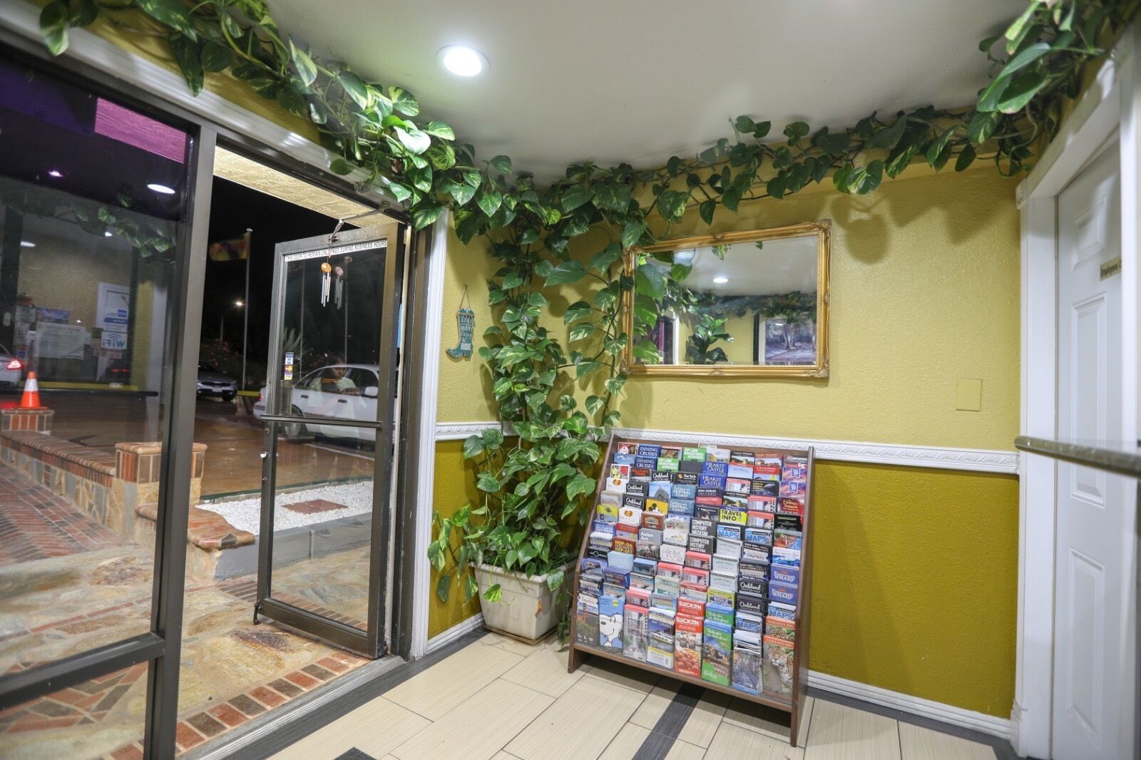 A reception area with a glass door, a bulletin board with travel brochures, and a mirror on the wall.