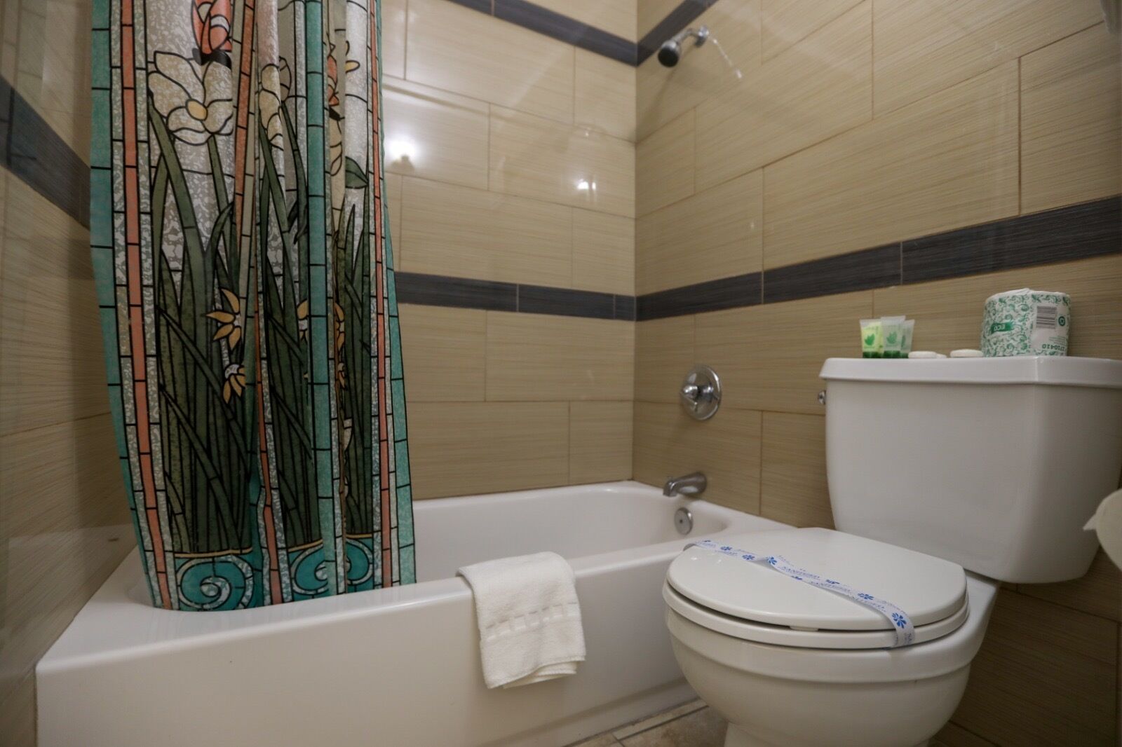 Un baño con bañera, inodoro y cortina de ducha con motivos florales.