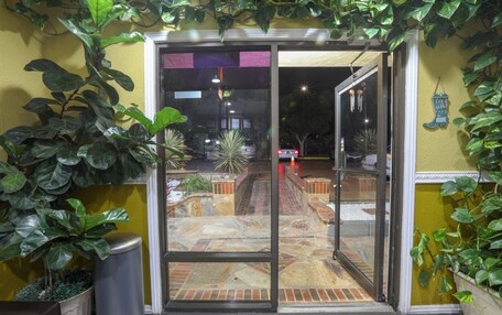 A glass door entrance to a building with a tiled patio area visible through the door.